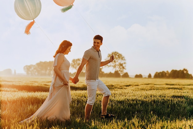 Couple d'amoureux marchant sur le terrain avec des boules de couleur hélium