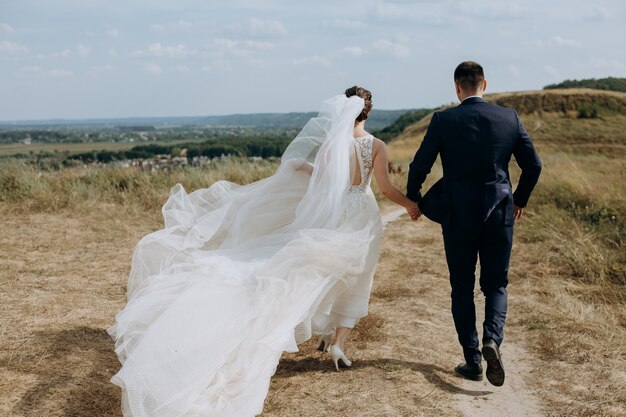 Couple amoureux mariage ensemble à l'extérieur chemin de champ paysage ciel voile vent liberté