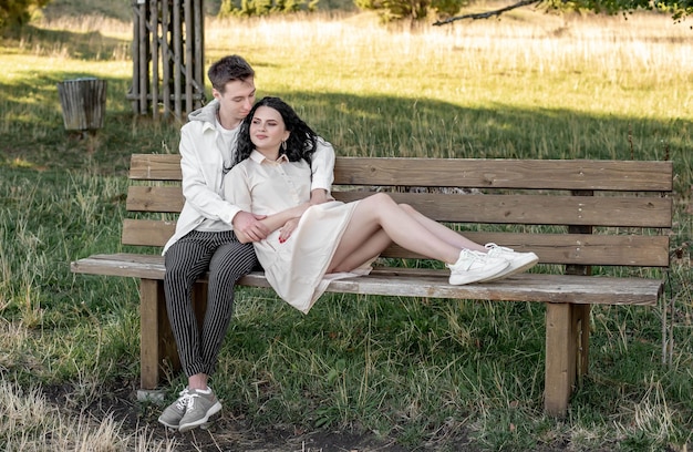 Un couple amoureux, un mec et une fille s'assoient sur un banc et se caressent, s'embrassent