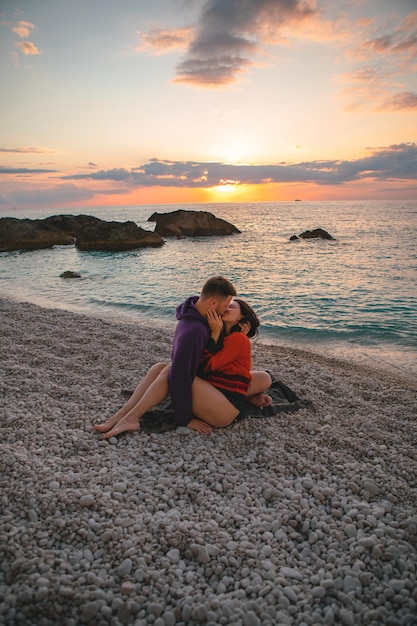 Couple amoureux à la plage profitant du temps ensemble et du coucher du soleil au-dessus de la mer Grèce vacances île de Lefkada