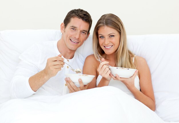 Couple d&#39;amoureux prenant son petit déjeuner allongé sur son lit