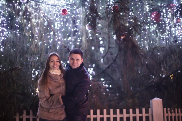 Couple d'amoureux près de l'arbre de Noël dans la nuit en plein air