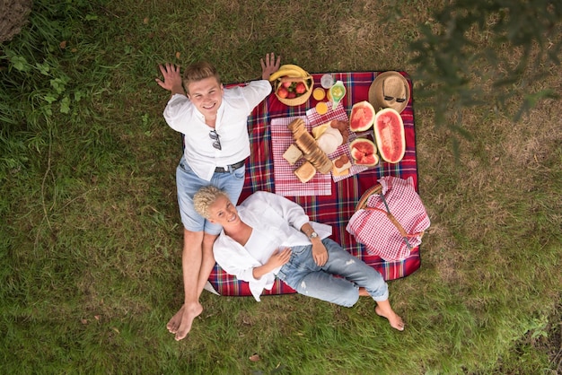 Couple amoureux profitant de l'heure du pique-nique boire et manger dans la belle nature sur la vue de dessus de la rive du fleuve