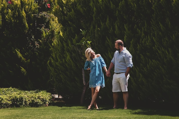 Couple d'amoureux profitant d'une lune de miel dans un hôtel de luxe, se promenant dans un parc avec des palmiers et des fleurs de beauté