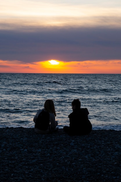 Couple amoureux regardant le coucher du soleil ensemble sur la plage