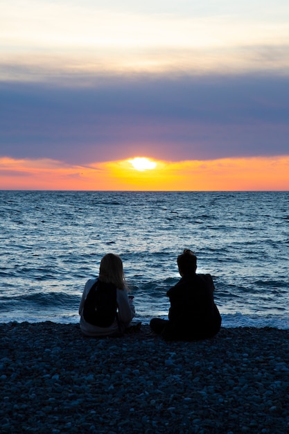 Couple amoureux regardant le coucher du soleil ensemble sur la plage