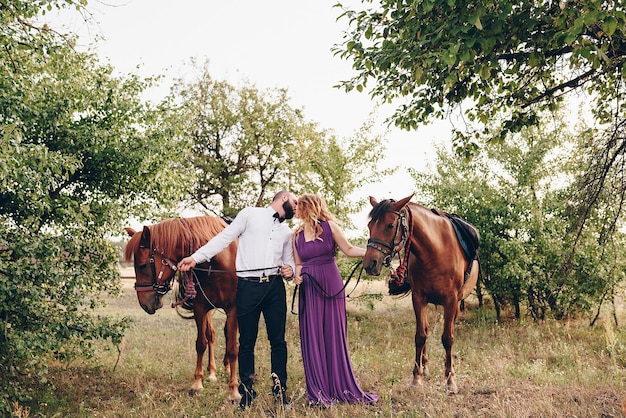 Un couple amoureux à un rendez-vous. Monter à cheval. Robe violette.