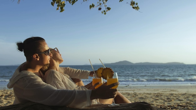 Couple d'amoureux en robe blanche lunettes de soleil en étreignant se détendre et