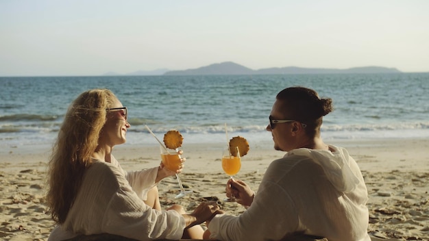 Couple d'amoureux en robe blanche lunettes de soleil se détendre et boire du coc