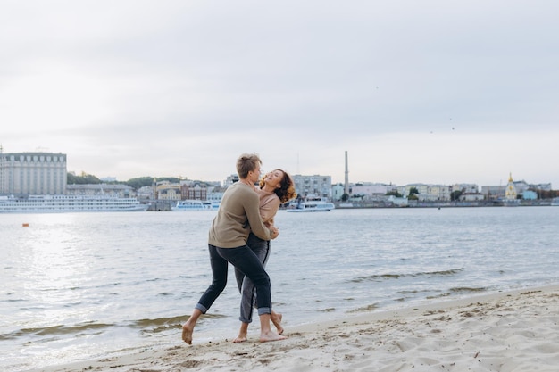 Couple amoureux s'amusant ils rient s'embrassent et profitent d'une chaude soirée d'été sur la plage