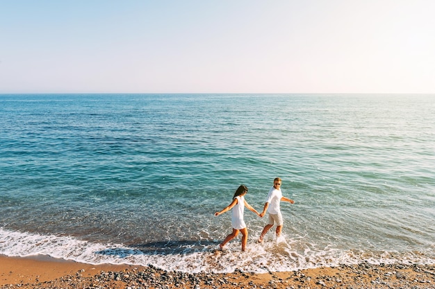 Photo couple amoureux s'amuser sur la plage. voyage de noces. le couple voyage. homme et femme sur la plage. couple heureux. courez le long du rivage. tour en mer. homme et femme en mer. voyage de mariage. les amoureux