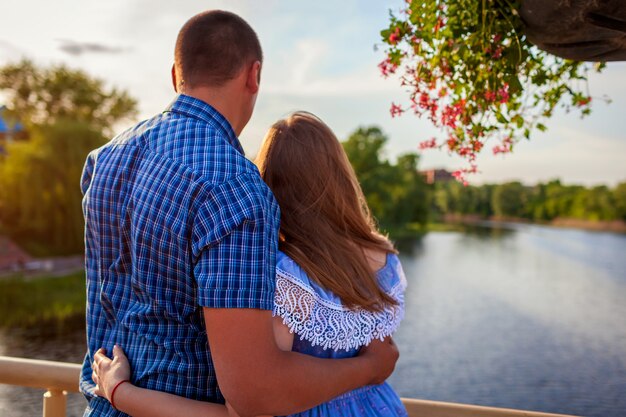 Couple amoureux s'embrassant et profitant d'une vue sur la rivière depuis un pont au coucher du soleil