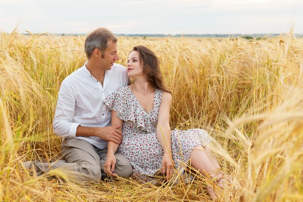 Un couple d'amoureux s'embrasse sur un champ de blé. Homme et femme sur la prairie d'été. Un rendez-vous romantique