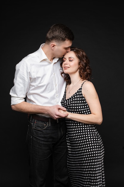 Couple d'amoureux se blottissant sur le mur noir. Concept d'amour.