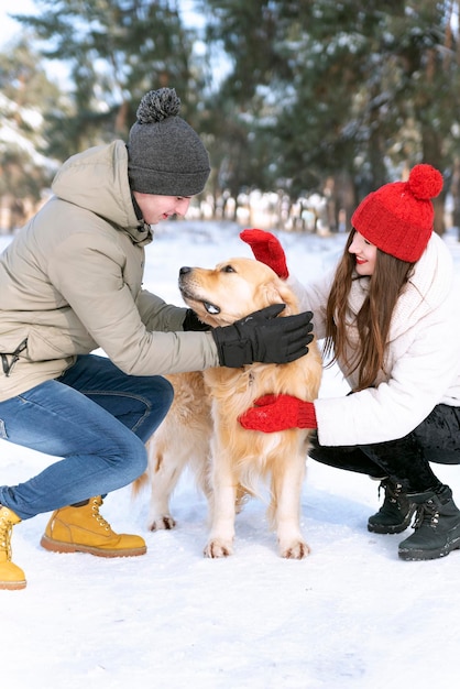 Un couple d'amoureux se promène dans la forêt d'hiver avec un chien. Jeune famille heureuse. Cadre vertical.