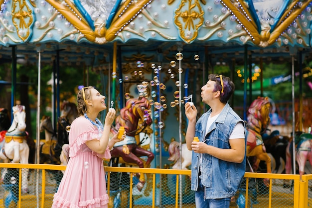 Couple amoureux se souffle des bulles de savon, ils sont heureux et rient dans un parc d'attractions