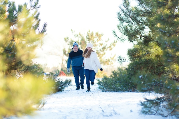 Un couple d'amoureux se tenant la main traverse la forêt d'hiver. Riez et passez un bon moment.