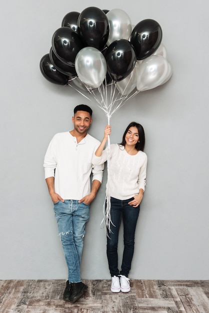 Couple d'amoureux souriant tenant des ballons.