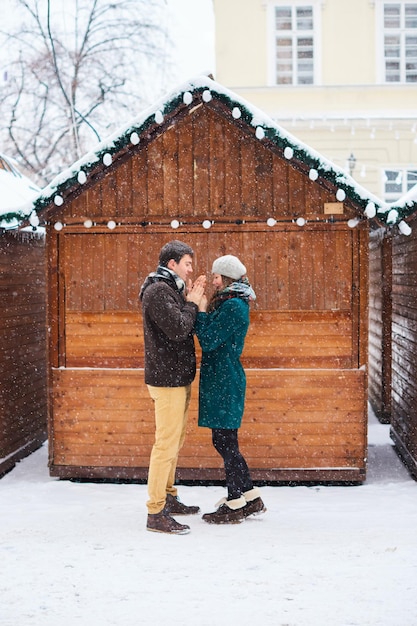 Couple amoureux sous la neige Il se réchauffe les mains