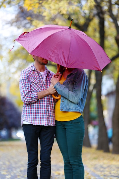 Couple d'amoureux sous un parapluie dans le parc d'automne