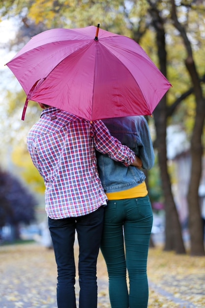 Couple d'amoureux sous un parapluie dans le parc de l'automne