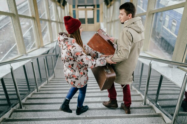 Couple d'amoureux de style de vie transportant des valises dans les escaliers.