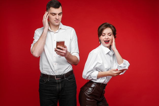 Couple amoureux surfer sur Internet, photo isolée sur mur rouge