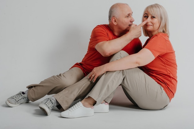 couple amoureux en t-shirts orange riant et étreignant sur fond blanc