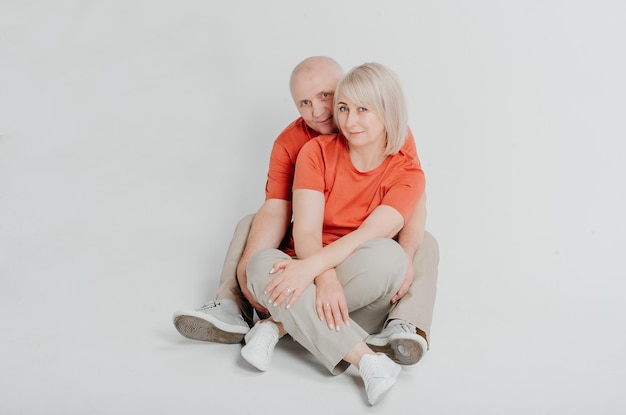 couple amoureux en t-shirts orange riant et étreignant sur fond blanc