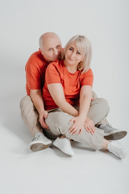couple amoureux en t-shirts orange riant et étreignant sur fond blanc