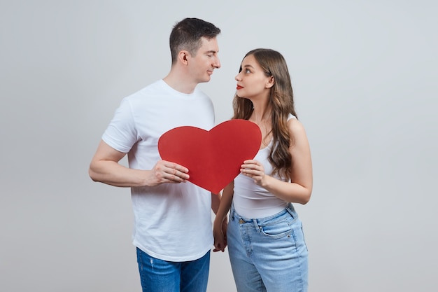 Un couple amoureux tient un cœur en papier rouge, se regardent. Joyeuse saint Valentin.