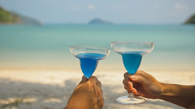 Le couple amoureux tient un verre de cocktail de curaçao bleu sur