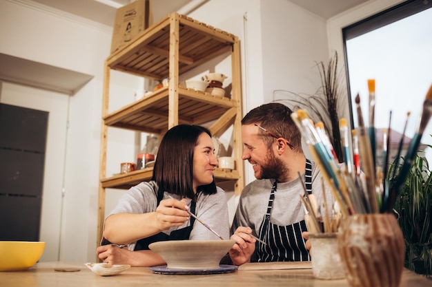 Couple amoureux travaillant ensemble sur la roue de potier dans l'atelier de l'atelier d'artisanat