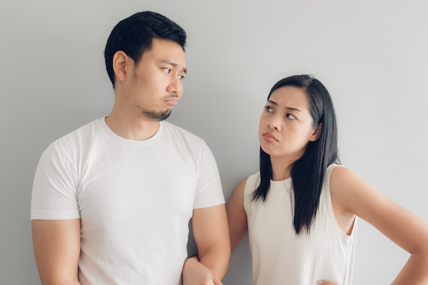 Couple amoureux triste en t-shirt blanc et fond gris.