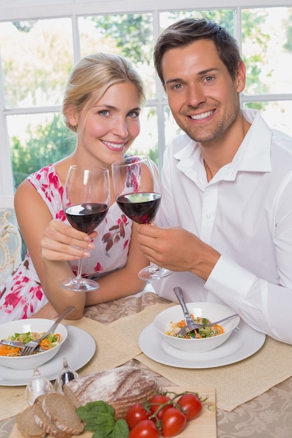 Couple d&#39;amoureux avec des verres à vin assis à la table à manger