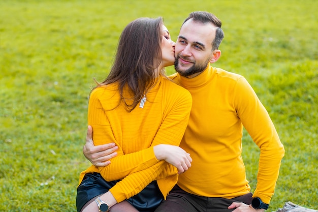 Couple d'amoureux vêtus de cols roulés jaunes dans le parc étreignant