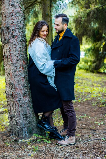 Couple amoureux vêtus de manteaux dans les bois