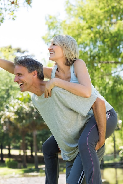 Couple appréciant piggyback ride dans le parc