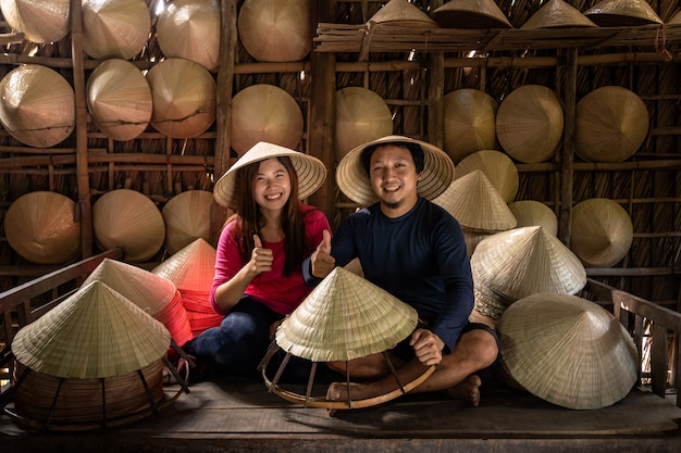 Couple d&#39;artisan voyageur asiatique faisant le chapeau vietnamien traditionnel dans la vieille maison traditionnelle