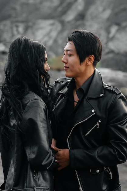 Un couple asiatique amoureux dans des vêtements en cuir noir se promène dans la nature parmi les arbres. Style, mode, amour