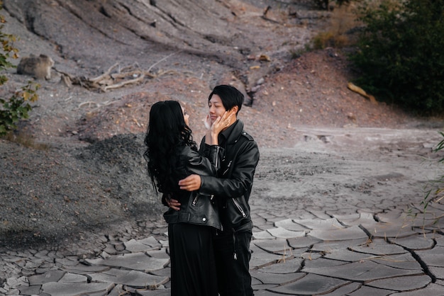 Un couple asiatique amoureux dans des vêtements en cuir noir se promène dans la nature parmi les arbres. Style, mode, amour