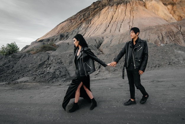 Un couple asiatique amoureux dans des vêtements en cuir noir se promène dans la nature parmi les arbres. Style, mode, amour