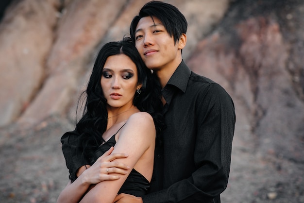 Un couple asiatique amoureux dans des vêtements en cuir noir se promène dans la nature parmi les arbres. Style, mode, amour