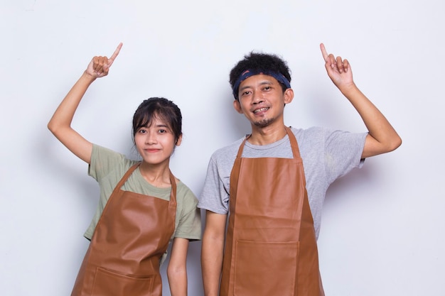 Un couple asiatique barista serveur porte un tablier pointant avec les doigts vers différentes directions sur blanc