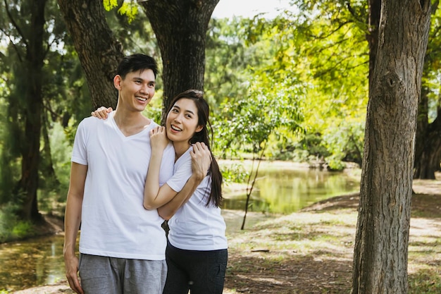 Un couple asiatique en bonne santé se promène dans le jardin en se liant à la nature ombragée le matin très heureux.