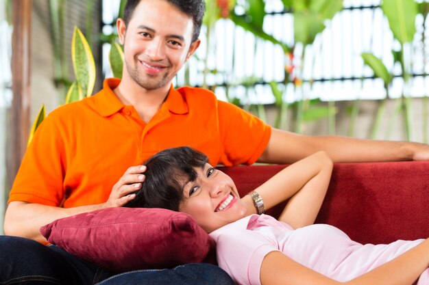 Couple asiatique dans une maison spacieuse sur un canapé