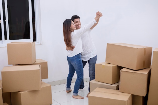 Un couple asiatique danse dans leur nouvelle maison.