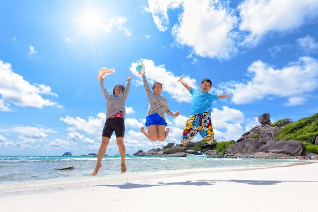 Un couple asiatique et une famille d'adolescents voyagent en vacances sautent ensemble, s'amusent et sont heureux sur la plage, le soleil de l'océan d'Andaman et les nuages sur le ciel bleu en été, vacances en mer, voyage en Asie, île de Similan, Phuket, Thaïlande