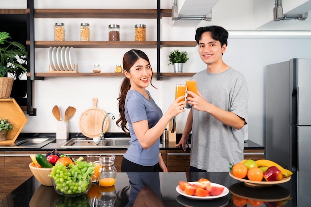 Un couple asiatique heureux aime boire un smoothie végétalien sain dans le comptoir de la cuisine Couple faisant un smoothie végétalien ensemble à la maison pour un mode de vie sain