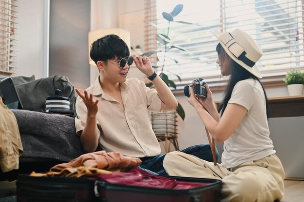 Un couple asiatique heureux emballant un sac de voyage pour les vacances d'été dans le salon Concept de vacances et de style de vie de voyage